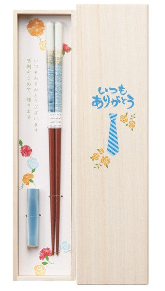 A set of chopsticks in blue colors with a floral patterned chopstick rest, presented in a wooden box with Japanese gratitude phrases and flower illustrations.