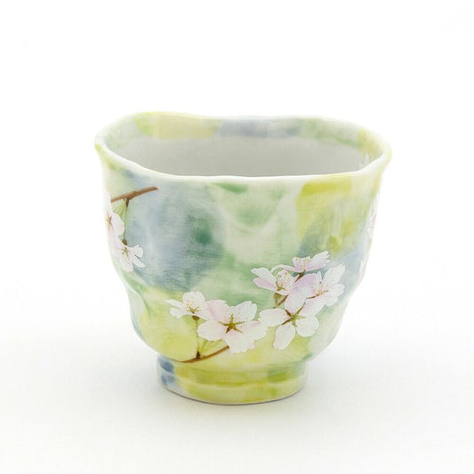 A ceramic tea cup with a floral pattern, featuring pink cherry blossoms on a soft background.