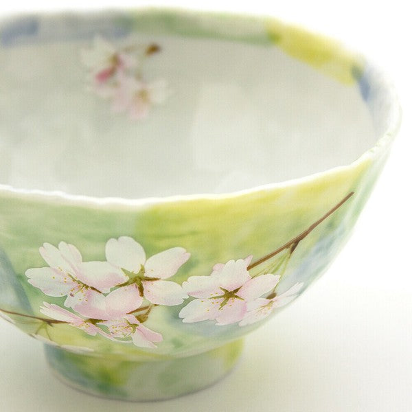 Close-up of cherry blossom design on light green ceramic rice bowl, showcasing the lifelike floral print and fine detail.