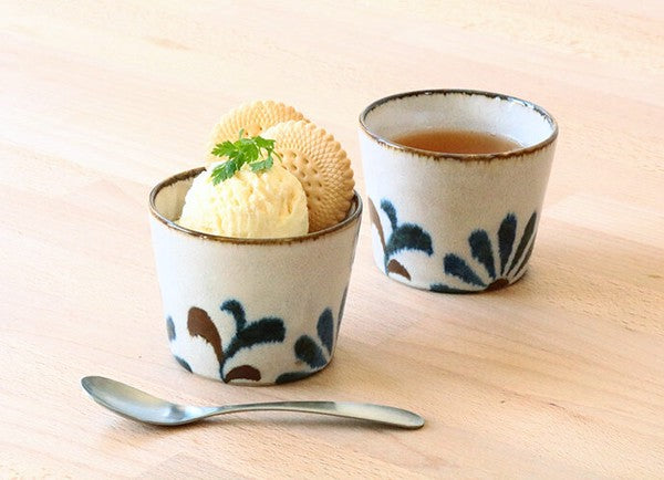 Two ceramic cups with Yachimun-style patterns, one containing a scoop of ice cream, the other with a cup of tea, on a wooden surface with a spoon