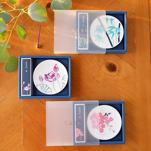 Complete Fushikaden incense set of three, each with a porcelain plate, holder, and incense sticks in an elegant gift box, displayed on a wooden surface with a green plant in the background.