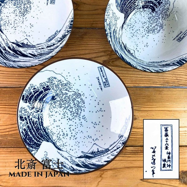 A set of large ceramic bowls with a white base and blue wave pattern, based on Katsushika Hokusai's artwork 'The Great Wave off Kanagawa'.