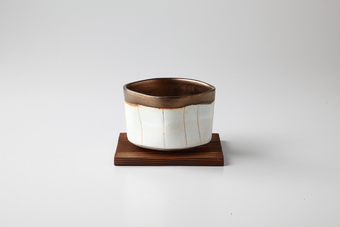 The bowl in solid white with gold stripes on a coaster.