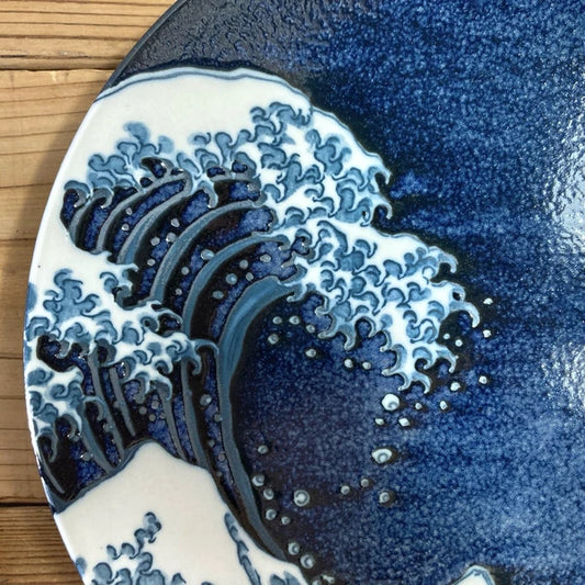 Close‑up of ceramic surface showing intricate wave crest design and fine porcelain glaze