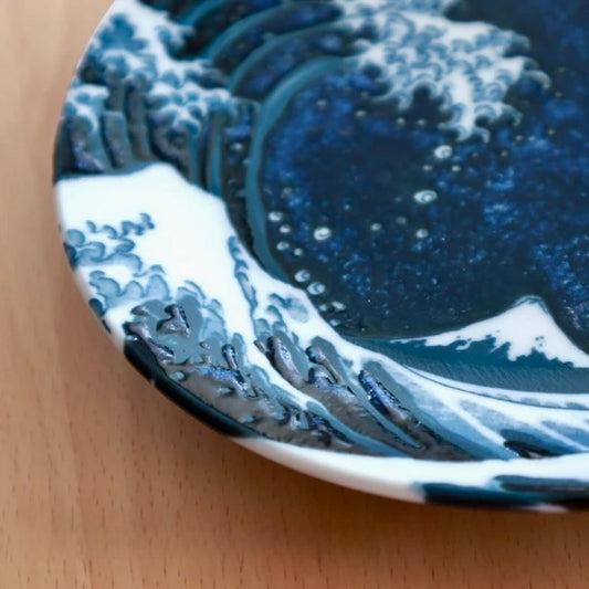 Close-up of Hokusai’s Great Wave artwork on ceramic plate, showing cresting wave and Mount Fuji