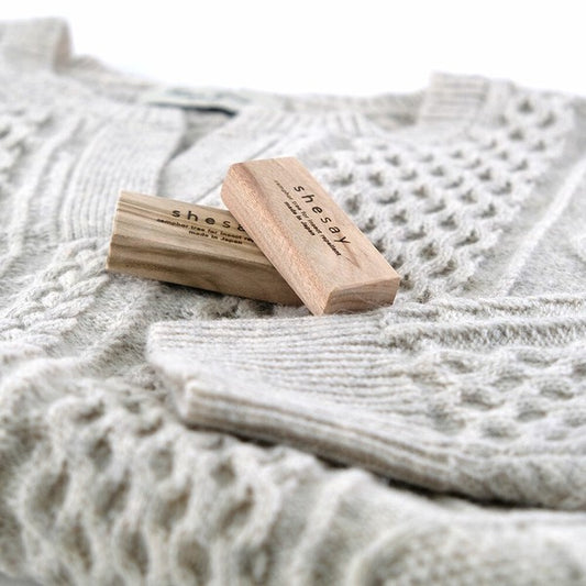 Camphor insect repellent block placed on folded sweater for moth protection