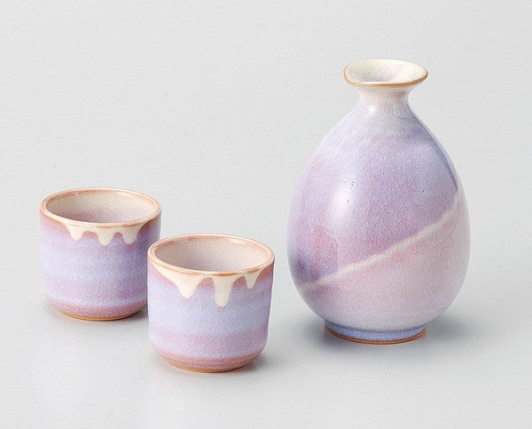 Handcrafted Hagi Ware sake set with purple murasaki glaze, including a sake pourer and two cups with natural blush tones and crackle finish