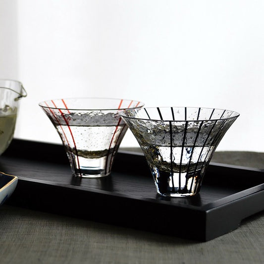 Seasonal Edo glass sake cups filled with sake, displayed together on a wooden table