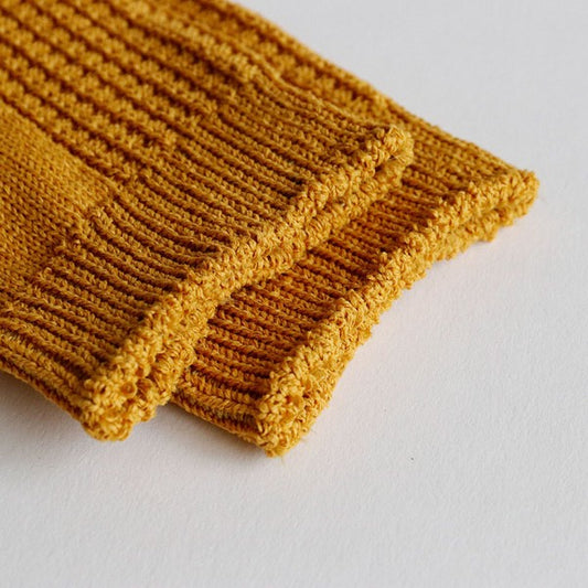 Close-up of textured washi yarn fabric in mustard socks, showing crisp and airy weave