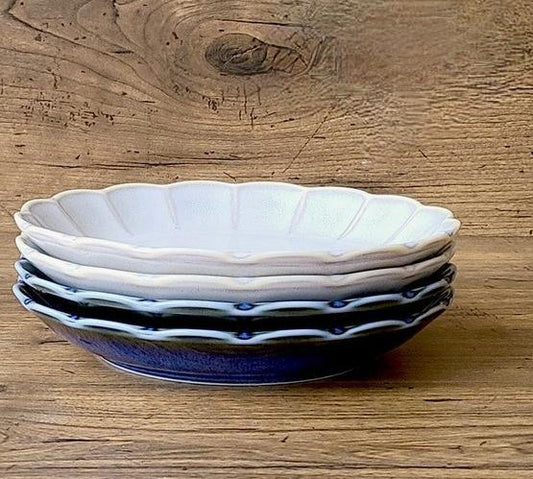 Stack of flower-shaped Yūgawari glaze plates in blue and grey, highlighting their layered petal design and subtle color variations