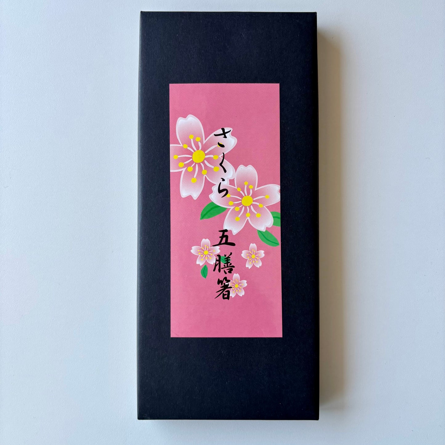 Black rectangular box with a pink label featuring cherry blossoms and Japanese text on a light gray background.