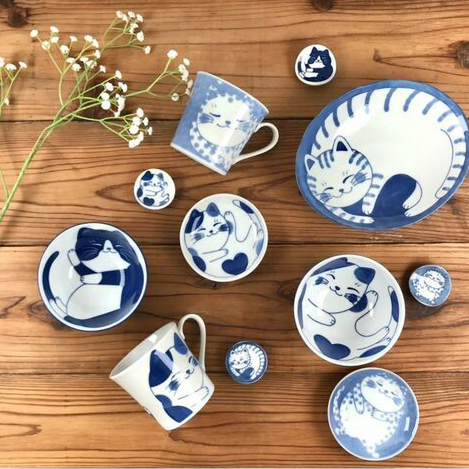Complete Nekochigura cat-themed tableware collection displayed together, featuring matching bowls, plates, and accessories with playful blue feline illustrations in traditional Mino ware style