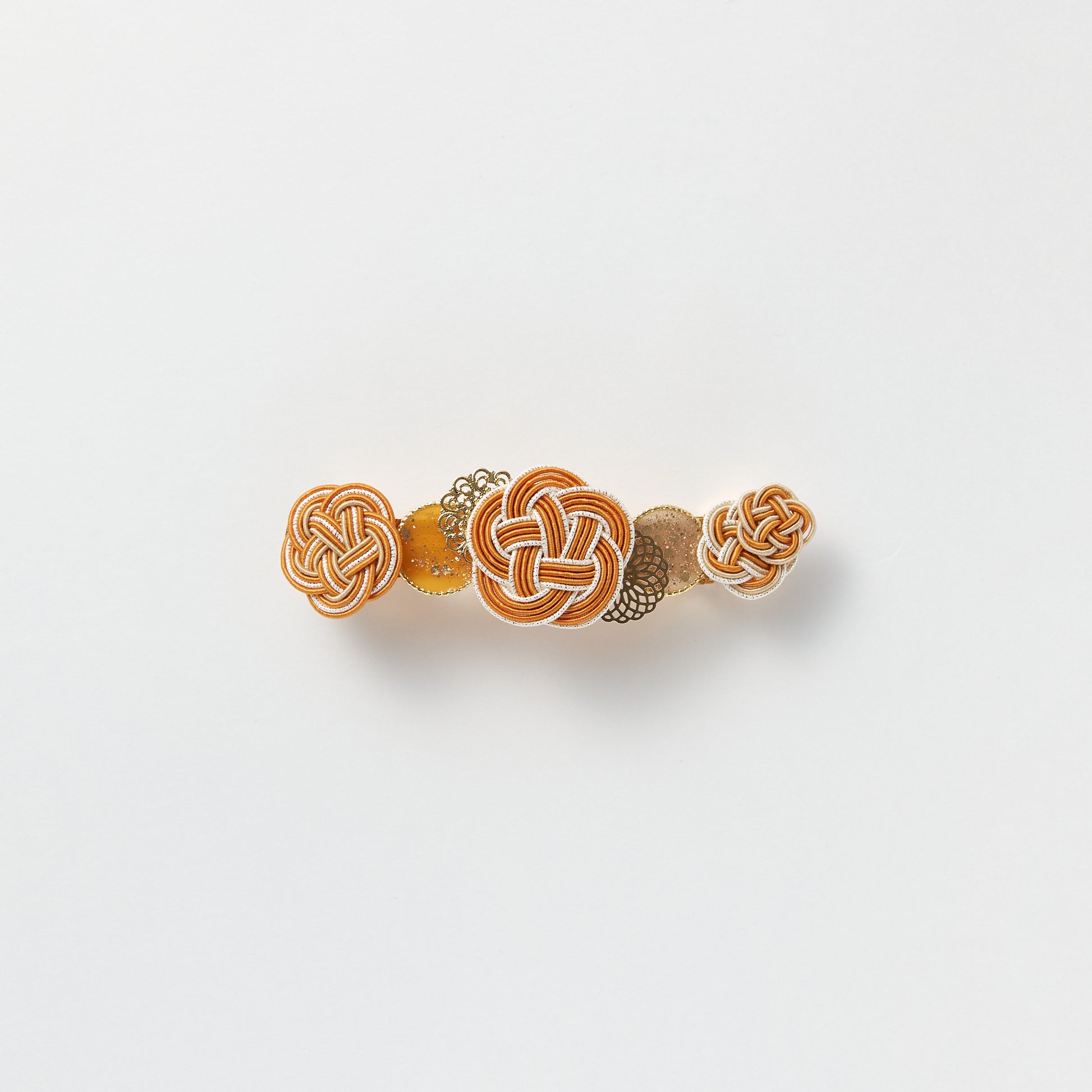 Front view of handmade Plum Blossom Knot Barrette in orange, featuring silk-wrapped mizuhiki knot