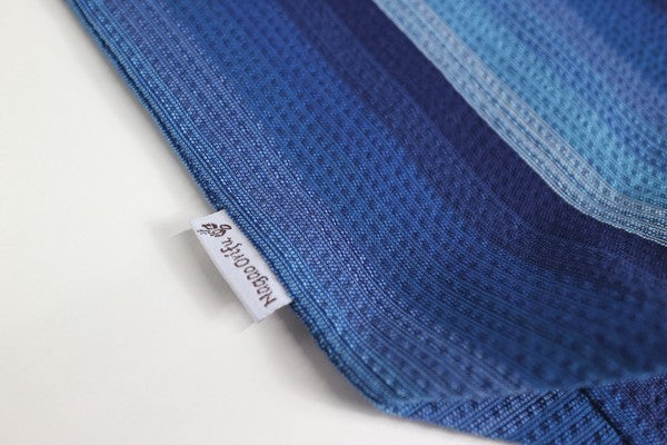Close-up of Awa Shijira-ori cotton fabric showing the signature crinkled shibo texture in navy gradient stripes