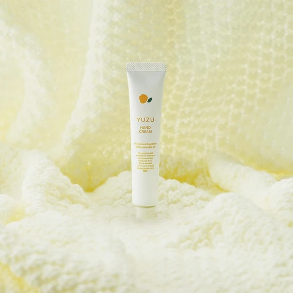 Yuzu hand cream tube on a textured yellow background