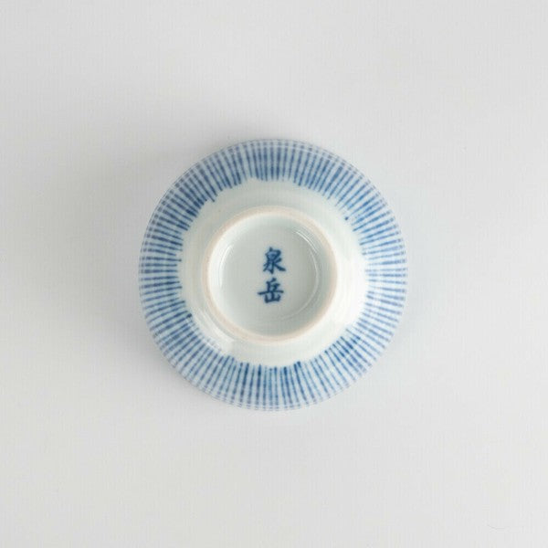Bottom view of vertically striped porcelain teacup with unglazed foot and kiln mark