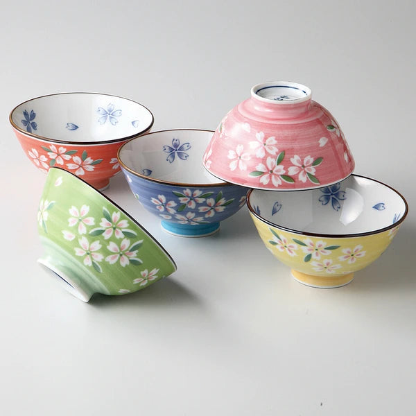 Set of five ceramic rice bowls in different pastel tones, each decorated with delicate sakura blossom patterns