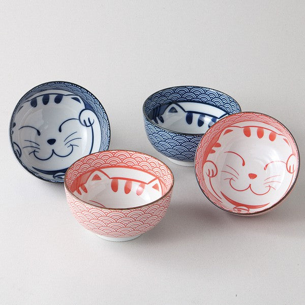 Set of four Japanese ceramic bowls featuring smiling cat designs and traditional Seigaiha wave patterns in red and blue, gift boxed, made in Japan.