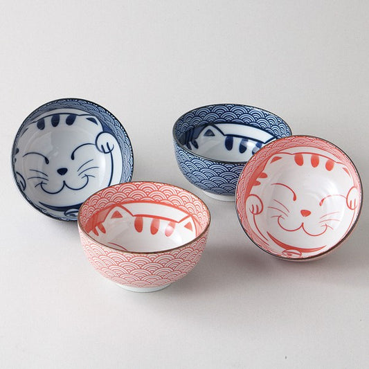 Set of four Japanese ceramic bowls featuring smiling cat designs and traditional Seigaiha wave patterns in red and blue, gift boxed, made in Japan.