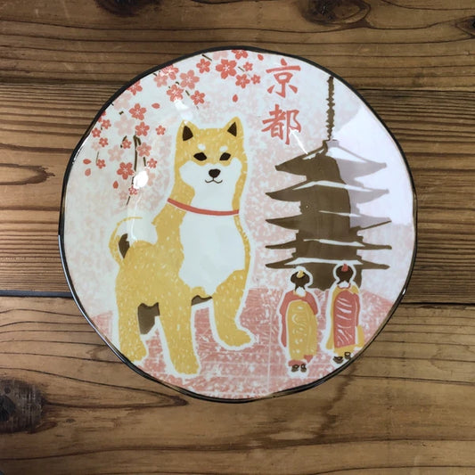 A ceramic plate with a Shiba Inu dog and cherry blossom design, featuring Kyoto landmarks.