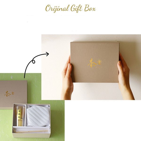 Brown gift box with gold emblem held by hands, showing the inside contents on a green surface.