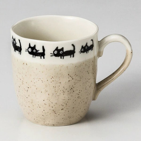 Beige Mino ware mugs with black cat illustrations, featuring playful poses and simple ceramic form