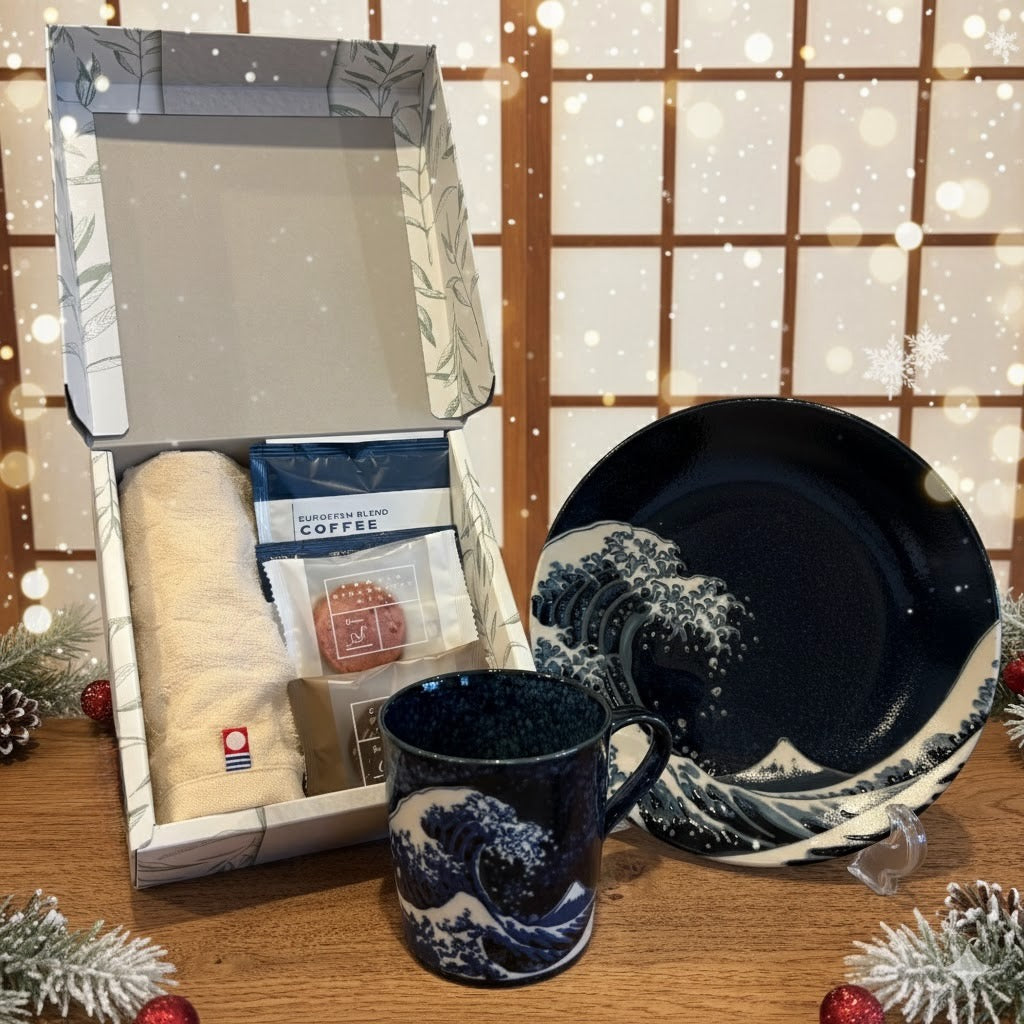 Great wave-patterned mug and plate with gift box containing coffee and towel on a wooden surface.