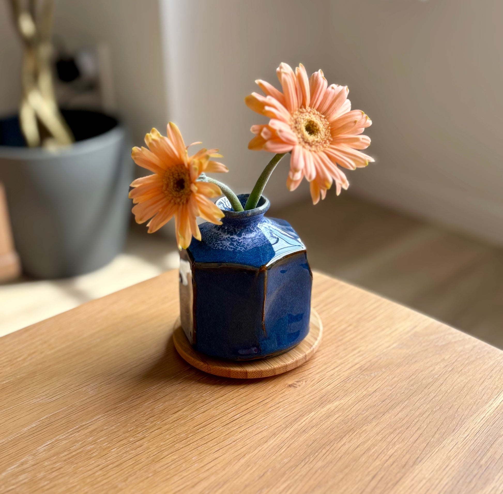 Mini Japanese blue vase with two orange flowers on a wooden surface