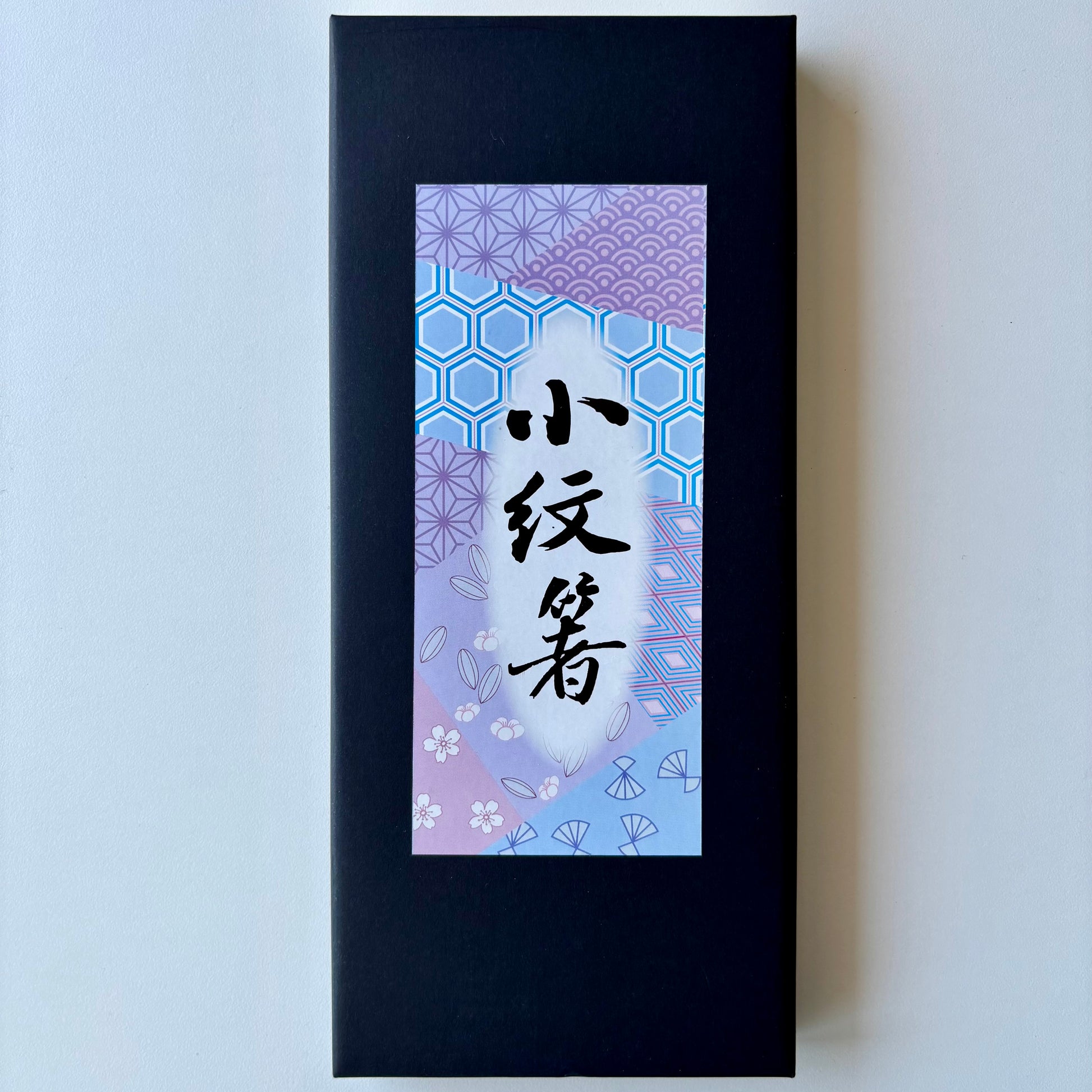 Black rectangular box with a decorative purple label featuring Japanese characters on a light gray background