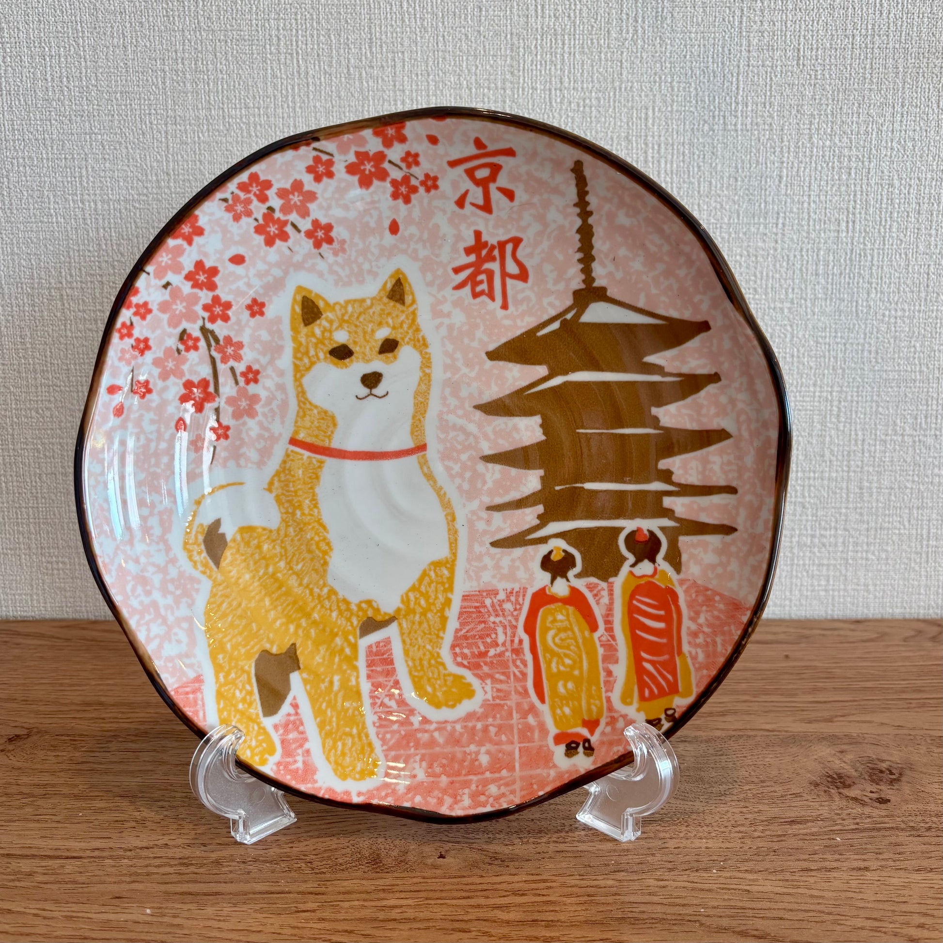 A ceramic plate with a Shiba Inu dog and cherry blossom design, featuring Kyoto landmarks.